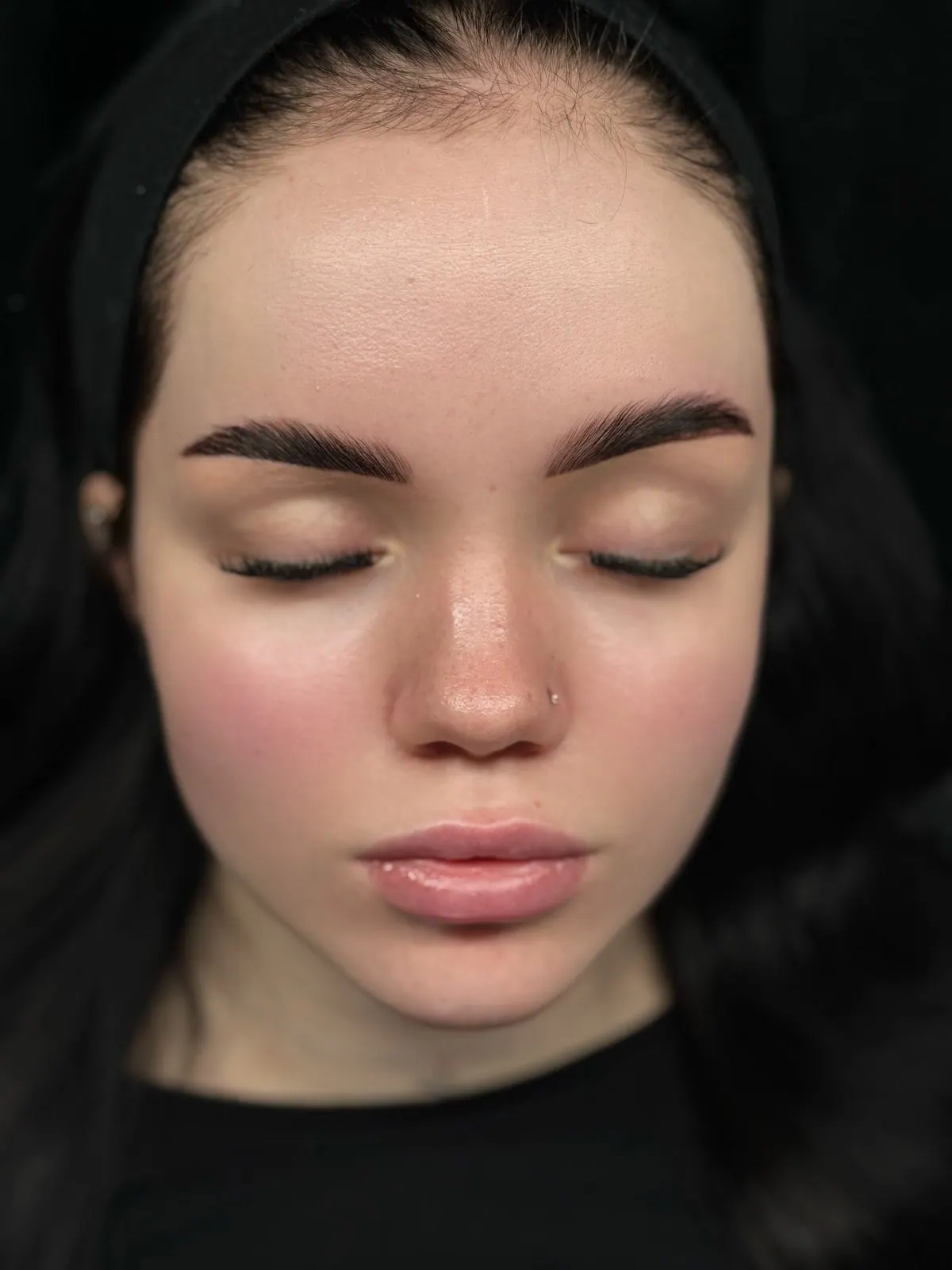 Browlifting: kräftige, gleichmäßig gestylte Augenbrauen, Porträt von vorne mit geschlossenen Augen